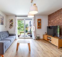 Wohnzimmer in einem Einfamilienhaus mit Ziegelwand, bequemer Couch und Holzboden.