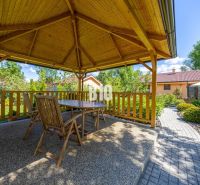 Ein hölzerner Pavillon mit Sitzgelegenheiten im Garten eines Einfamilienhauses in Bíkové Humence.