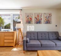Wohnzimmer mit Sofa, Bildern und Holzboden in einem Einfamilienhaus.