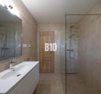 Modernes Badezimmer mit großem Spiegel, Duschkabine und minimalistischer Ausstattung.