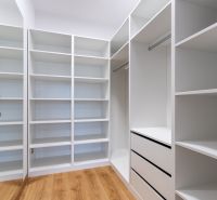 Heller Kleiderschrank mit viel Stauraum und Boden in Holzoptik.