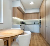 Küche mit Tisch in einer 3-Zimmer-Wohnung, Boden mit Holzdekor und eingebauten Geräten.
