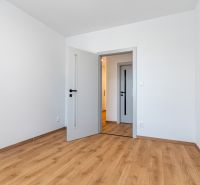 Weißer Raum mit Holzboden und Türen in einer 3-Zimmer-Wohnung.