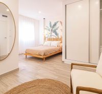 Innenraum einer Ferienwohnung mit Bett, Spiegel und Boden in Holzoptik.