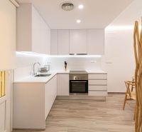Küche in einer Ferienwohnung mit weißen Schränken und einem Boden in Holzoptik.