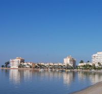Die Küste mit Ferienwohnungen in La Manga del Mar Menor am ruhigen Meer und blauem Himmel.