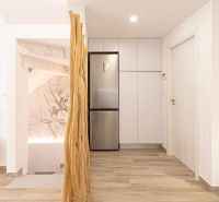 Innenraum einer Ferienwohnung mit Küchenschränken, Kühlschrank und Bodenbelag in Holzoptik.