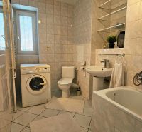 Badezimmer einer 2-Zimmer-Wohnung mit Badewanne, Waschbecken, Waschmaschine und Toilette.