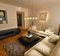 Wohnzimmer mit Ledersofa, Glastisch und Holzboden in einer Zweizimmerwohnung.