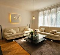 Wohnzimmer in einer 2-Zimmer-Wohnung mit weißem Sofa und Boden in Holzoptik.