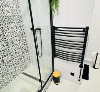 Badezimmer mit Duschkabine und schwarz-weißen Dekorationen in einer Einzimmerwohnung.