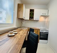 Küche in einer Einzimmerwohnung mit Holzboden, weißen Schränken und Geräten.