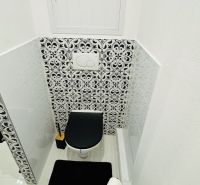 Toilette mit schwarz-weißem Fliesenmuster in einer Einzimmerwohnung.