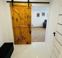Innenraum mit Schiebetüren aus Holz, die in ein Einzimmerapartment mit Holzboden führen.