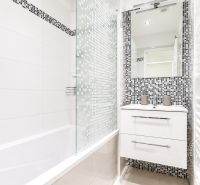 Badezimmer mit Badewanne und Mosaikfliesen in einer 2-Zimmer-Wohnung, elegantes Design.