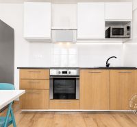 Küche in einer 2-Zimmer-Wohnung mit Holzboden und einem Kühlschrank aus Edelstahl.