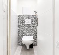 Toilette mit Mosaikfliesen in einer 2-Zimmer-Wohnung, Boden mit Holzdekor.