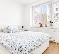 Schlafzimmer in einer 2-Zimmer-Wohnung mit Holzboden und großen Fenstern.