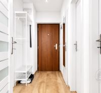 Weißer Flur in einer 2-Zimmer-Wohnung mit Holzboden und Sicherheitstür.