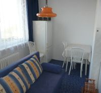 Ein Zimmer mit einem blauen Sofa und einer orangefarbenen Lampe in einer Zweizimmerwohnung.