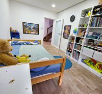 Kinderzimmer in einer 3-Zimmer-Wohnung mit Bett, Regalen und Boden in Holzoptik.