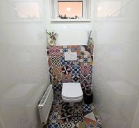 Badezimmer in einer 3-Zimmer-Wohnung mit gemusterten Fliesen und weißer Sanitärausstattung.
