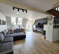 Offenes Wohnzimmer in einer 3-Zimmer-Wohnung mit Holzboden und bequemen Sitzgelegenheiten.