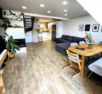 Wohnzimmer einer 3-Zimmer-Wohnung mit Sofa, Esstisch und Holzboden.