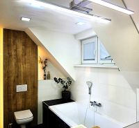 Badezimmer in einer 3-Zimmer-Wohnung mit Badewanne, Waschbecken und einem stufenförmigen Dach.