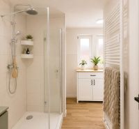 Badezimmer mit Duschkabine und Boden in Holzoptik in einer 2-Zimmer-Wohnung.