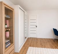 Arbeitsbereich mit weißem Tisch, blauem Stuhl und Holzboden in einer Zweizimmerwohnung.