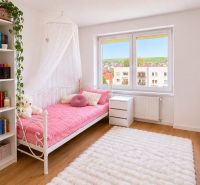 Ein Zimmer in einer 2-Zimmer-Wohnung mit einem weißen Bett, einem Regal und einem Boden in Holzoptik.