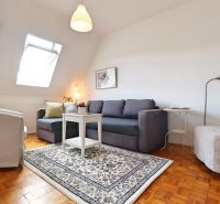 Wohnzimmer in einer 2-Zimmer-Wohnung mit Sofa, Sessel und Teppich, Boden mit Holzdekor.