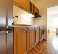 Küche mit Holzschränken in einer 2-Zimmer-Wohnung, Boden mit Holzdekor.