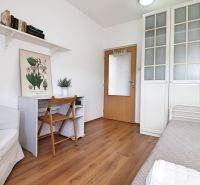 Ein Zimmer in einer 2-Zimmer-Wohnung mit einem Boden in Holzoptik, ein Schreibtisch und ein Stuhl.