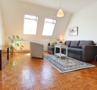 Wohnzimmer in einer 2-Zimmer-Wohnung mit Fenstern und Boden in Holzoptik.
