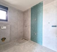 Badezimmer in einer 3-Zimmer-Wohnung mit grauen Fliesen und blauen Mosaiken an der Wand.