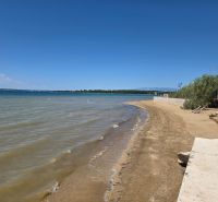 Ein Sandstrand am Meer in Privlaka mit klarem blauem Himmel und Wasser.