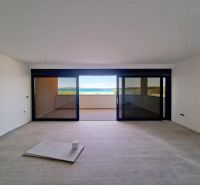 Wohnzimmer einer Dreizimmerwohnung mit Glaswand und Boden in Holzoptik.