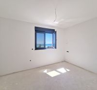 Ein leerer Raum ohne Möbel mit einem Fenster und Meerblick in einer 3-Zimmer-Wohnung.