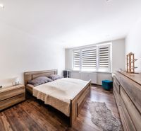 Schlafzimmer in einer 3-Zimmer-Wohnung mit Bett, Kommode und Boden in Holzoptik.