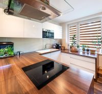 Küche in einer 3-Zimmer-Wohnung mit Holzboden und Fenstern mit Pflanzen.