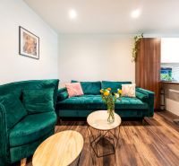3-Zimmer-Wohnung mit Sofa, Blumen auf dem Tisch und Holzboden.