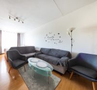 Wohnzimmer mit Holzboden in einer 3-Zimmer-Wohnung, graue Sofas, Glastisch.