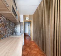 Küche mit Holzboden, Steinverkleidung und Schränken in einer 3-Zimmer-Wohnung.