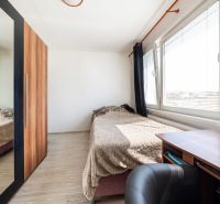 Ein Zimmer mit einem Bett, einem Schreibtisch und einem Schrank mit Spiegel in einer 3-Zimmer-Wohnung.