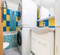 Badezimmer in einer 3-Zimmer-Wohnung mit Waschmaschine, Trockner und bunten Fliesen.