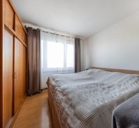 Schlafzimmer mit Bett, großem Schrank und Boden mit Holzdekor in einer 3-Zimmer-Wohnung.