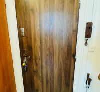 Holztür mit Türklingel in einer Einzimmerwohnung mit hellem Boden.