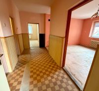 Helles Interieur eines Einfamilienhauses mit Fliesenboden, rosa Wänden und Holzverkleidungen.